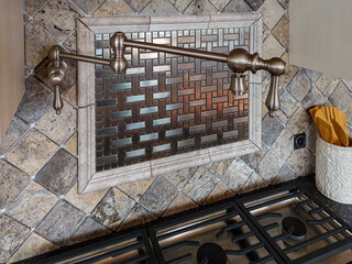 A pot filler faucet, also known as a pasta arm or kettle faucet over the stove.  Deluxe Kitchen...