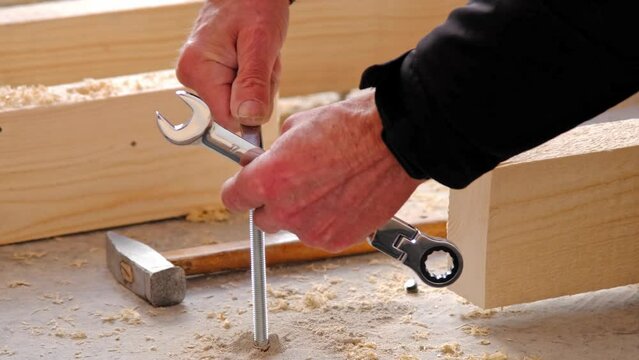 Hands of master twist washer with nut onto a threaded steel stud into concrete floor of rough floor for installation of wooden floor log. Repair and construction with your own hands - DIY. Slow motion