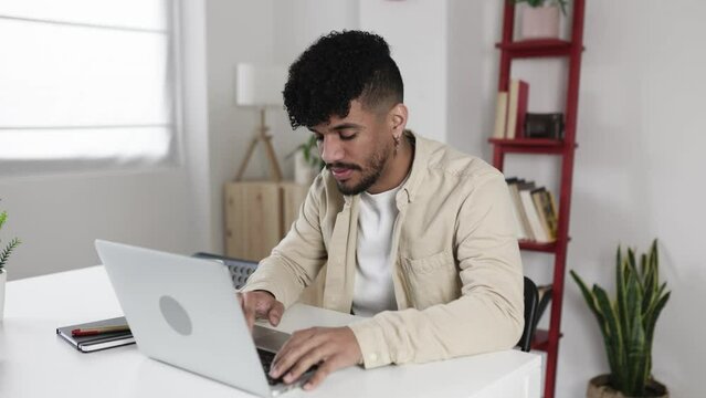 Concentrated young latino hispanic american man working on laptop from home. Education and e-learning concept with millennial person studying online - High quality 4k footage