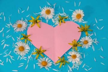 Fototapeta premium pink heart and flowers and petals around it, copy space on the heart, for some love message, flat lay