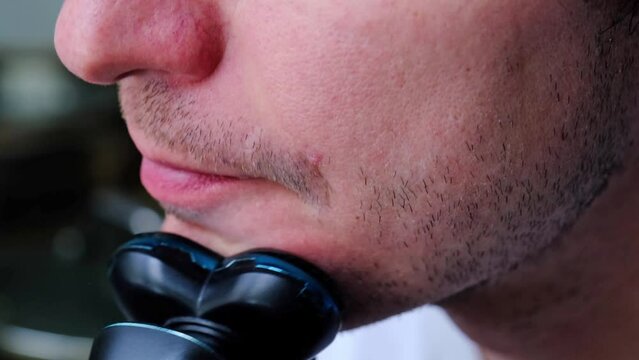 A man shaves with an electric razor close-up. Smooth shaving of light bristles. Slow Motion