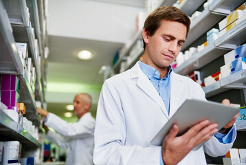 Fototapeta premium Dispensing duties just got smarter. Shot of a young pharmacist using a digital tablet in a pharmacy.