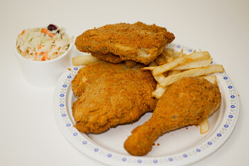 PIECES OF FRIED CHICKEN AND FRIES AND COLESLAW SALAD IN STUDIO  LIGHTING WHITE BACKGROUND