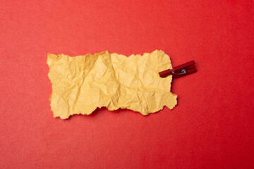 Piece of torn paper with clothespin on plain background