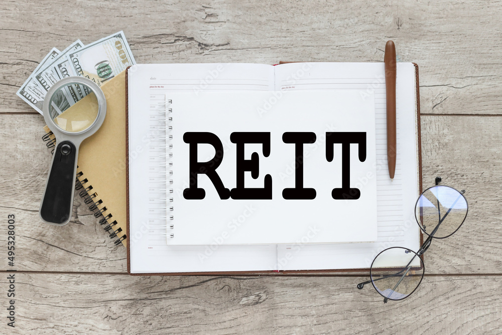 Poster reit - short for real estate investment trust. text on an open notepad on the table magnifier near t