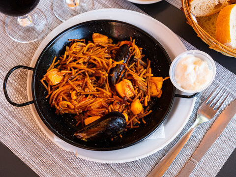 Popular dish valencian cuisine Fideua with seafood, made from shrimp, mussels, squid and noodles, served with sour cream