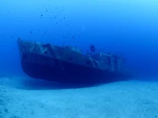 Gordijnen duikers die het scheepswrak verkennen en ontdekken onder water diepzeebodemmetaal op de oceaanbodem © underocean