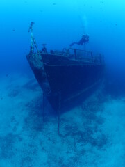 scuba divers exploring and discovering the ship wreck underwater deep sea bottom metal on ocean floor