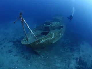 Gordijnen duikers die het scheepswrak verkennen en ontdekken onder water diepzeebodemmetaal op de oceaanbodem © underocean