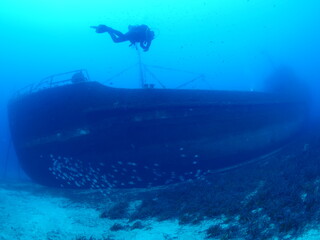 scuba divers exploring and discovering the ship wreck underwater deep sea bottom metal on ocean...