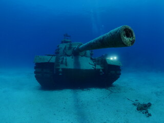 scuba divers exploring and taking photos tank wreck underwater