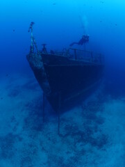 Obraz premium scuba divers exploring and discovering the ship wreck underwater deep sea bottom metal on ocean floor