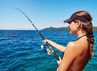 Im just reeling in the good times. Cropped shot of an attractive young woman fishing out at sea.