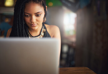 Her favourite blog spot. Cropped shot of an attractive young woman using her laptop in a coffee shop.