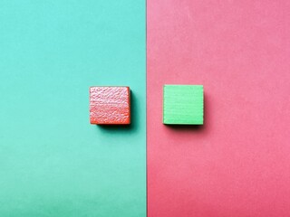 Top view red and green background divided diagonally with two matching color cubes placed on...