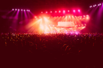 A crowded concert hall with scene stage in red lights, rock show performance, with people silhouette, colourful confetti explosion fired on dance floor air during a concert festival