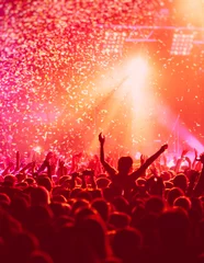 Poster A crowded concert hall with scene stage in red lights, rock show performance, with people silhouette, colourful confetti explosion fired on dance floor air during a concert festival © tsuguliev