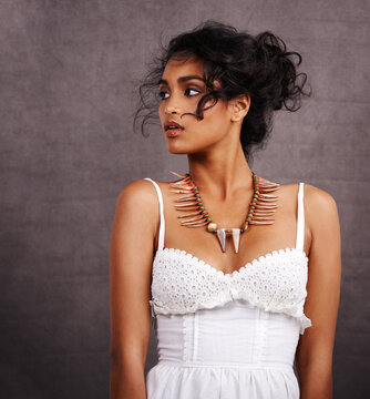 Damsel in a dress. Studio shot of a beautiful young ethnic woman in a white dress posing against a gray background.