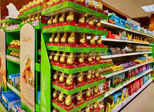 Ithaca, New York, US- March 26, 2022: Easter Holiday dedicated area in Wegmans, stocked with Lindt GOLD BUNNY Milk Chocolate. Easter bunny chocolate wrap in golden color aluminum foil with red collar