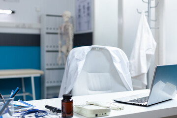 Inside of empty bright doctor office equipped with modern medical equipment used for clinical examination. Hospital room with nobody in it having pills bottle on table. Health are support services