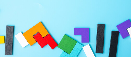 colorful wood puzzle pieces on blue background, geometric shape block with copy space. Concepts of...