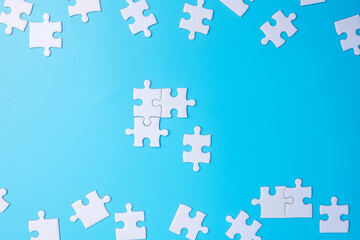 Group of white puzzle jigsaw pieces on blue background. Concept of solutions, mission, success,...