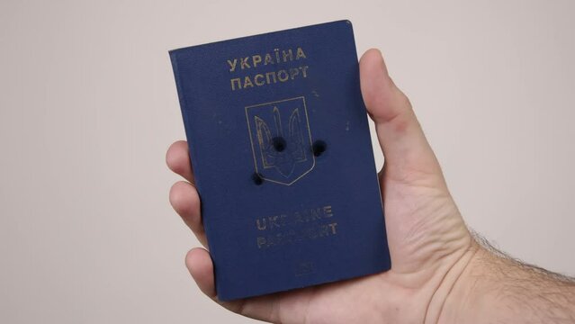 Ukrainian passport held by a man's hand. Holes in the document from gunshots. war in Ukraine. Russian aggression, occupiers