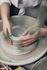 Hands close-up, men and women, a date in a pottery workshop, working together on one potter's wheel
