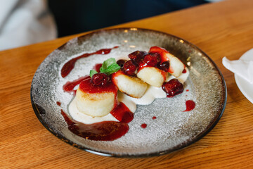 Syrniki, cottage cheese fritters with raspberry jam. Garnished with a mint leaf.