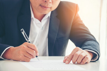 Obraz premium Businessman hand using pen signing on new contract to starting projects in conference room. Close up business manager man hands sign contract legal document in meeting room. Business agreement concept