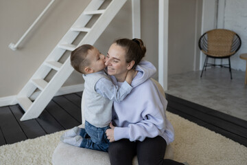 Happy mom and son hug, spend time at home together, look at each other. A mother on maternity leave plays with her son. Mother's Day. Preschool age. Home family cute photo.