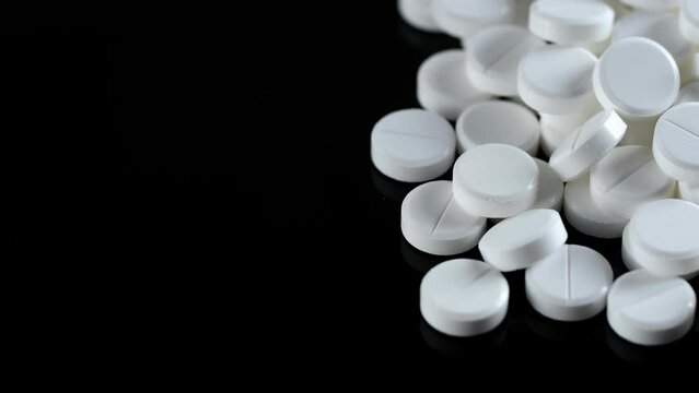 Many white round pills. Pharmaceutical production. Drugs on the production line. Moving background. close-up. view from above. white medical pills rotating closeup. Pills and drugs. Pharmaceutical