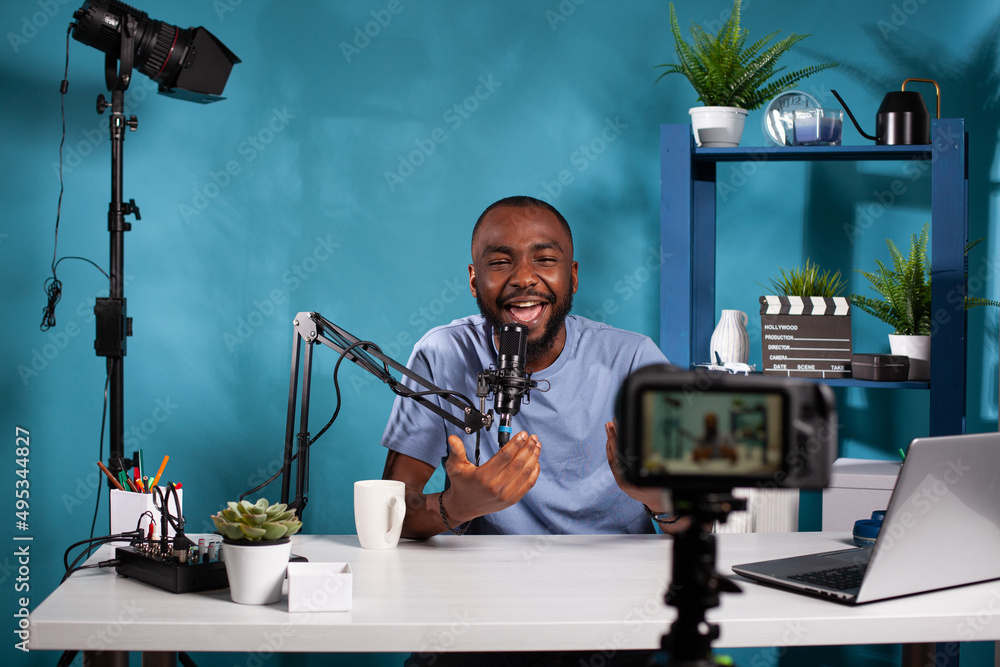 Poster exalted content creator in studio looking at dslr live video podcast setup during online live show. 
