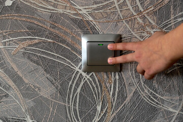 A gray switch located on the wall in the apartment. It is easy to turn on and off with both hand...