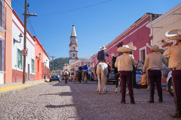 Los mariachis en caballos avanzan por la calle principal del pueblo mágico Mascota Jalisco.
