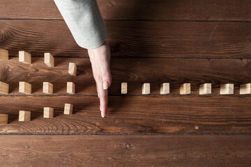 Businesswoman protecting dominoes from falling