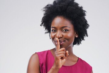 Fototapeta na wymiar Im good at keeping secrets. Portrait of an attractive young woman posing with her finger on her lips against a grey background.