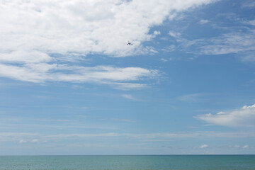 Fototapeta na wymiar Passenger plane flying over blue ocean. Blue sky with white cloud background