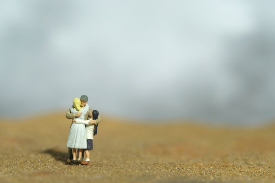 Miniature people toy figure photography. Family reunion concept. Father hugging his wife and daughter in the desert