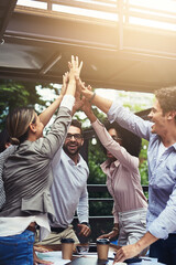 Meeting with a change of scenery. Shot of a group of colleagues high fiving during a meeting at a...