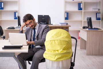 Young male employee looking after new born at workplace