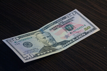 Fifty dollar banknote on dark wooden table texture