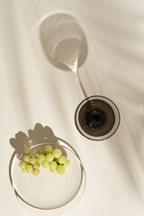 Sparkling wine in champagne glasses gray color glass and grape on beige background with beautiful shadows and caustic effect at sunlight. Summer alcoholic drinks concept. Vintage colored glass