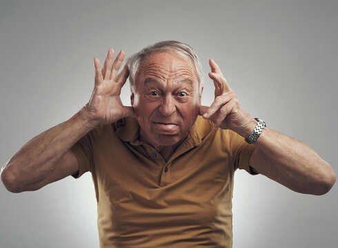 Int ouch with my inner child. Studio shot of an elderly man making a funny face against a grey background.