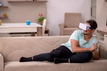Young man student wearing virtual glasses at home