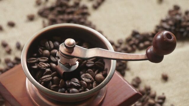 Preparing black coffee, coffee beans and manual coffee grinder on salt. Coffee beans are scattered on the table. Camera movement
