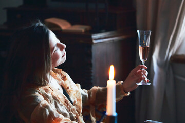 A beautiful woman drinks champagne at the hotel. Relaxes and enjoys life. Vertical photo.