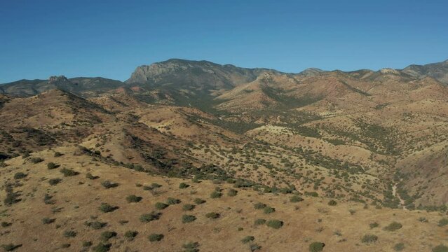 Aerial moving along ridge with arid desert mountains in background, 4K