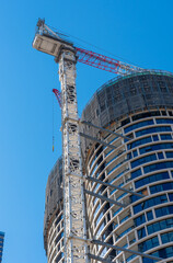 Melbourne, Australia, city apartment building under construction with a large crane against a clear blue sky