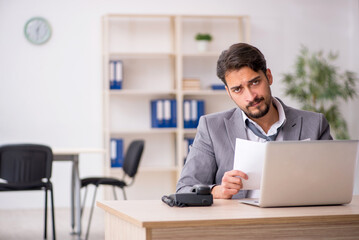 Young male employee and too much work in the office